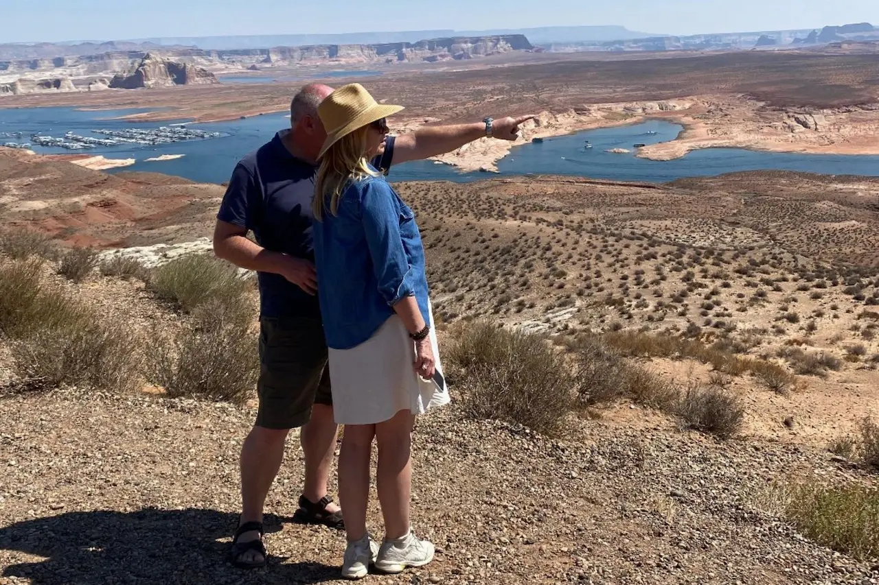 Zwei Reiseleiter stehen an einem Aussichtspunkt im Südwesten der USA und blicken über eine weite Wüstenlandschaft mit Fluss und Stausee