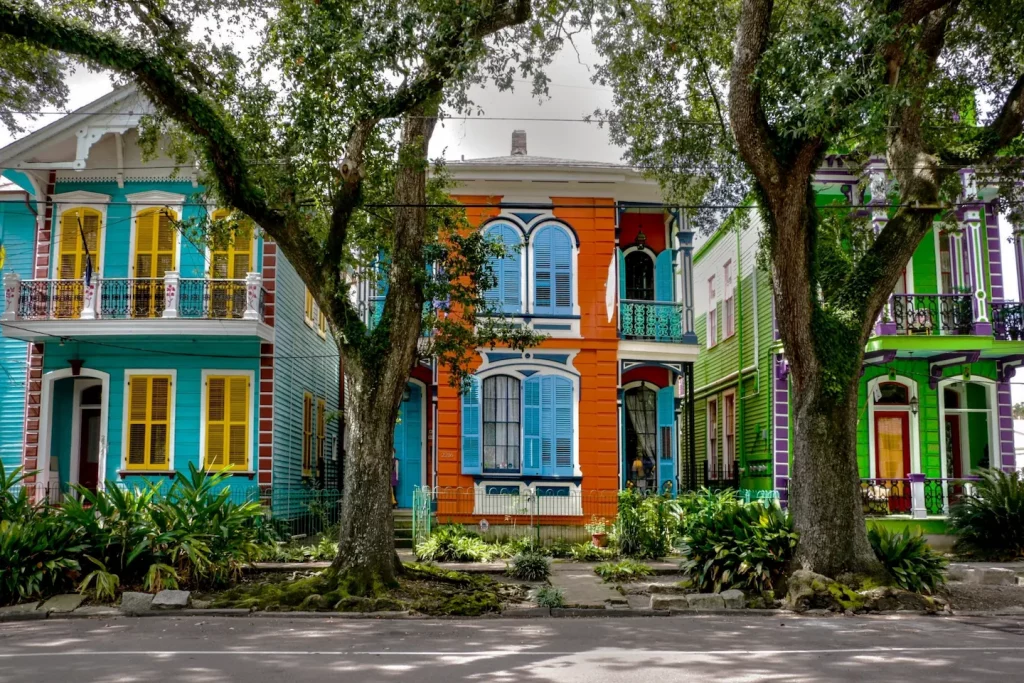 Bunte historische Wohnhäuser mit Balkonen und Fensterläden in einer von Bäumen gesäumten Straße
