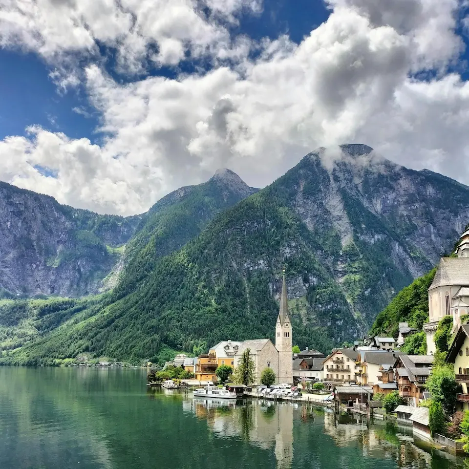 Ort Hallstatt am See mit Kirche, Häusern und steilen bewaldeten Bergen im Hintergrund