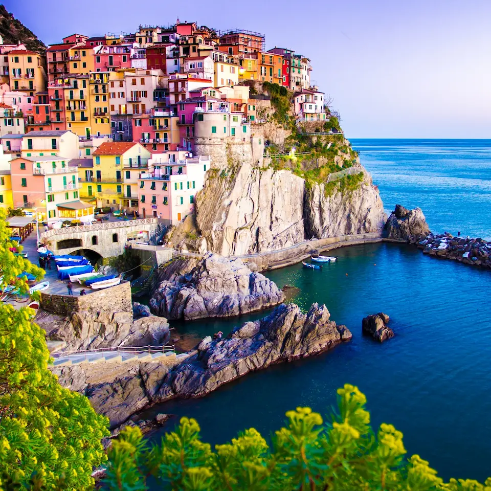 Farbenfrohes Küstendorf mit dicht stehenden Häusern an einer felsigen Steilküste direkt am Meer